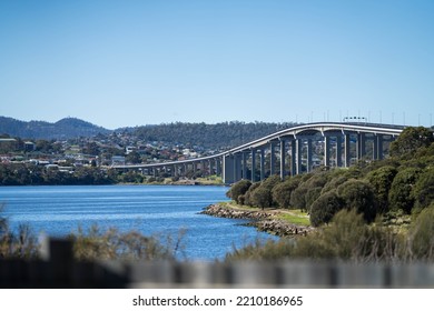 Tasman Bridge In Hobart Tasmania, Trees Under A Bridge Over A River