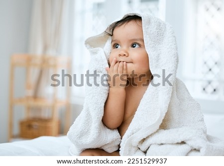I taste so fresh. Shot of an adorable baby covered in a towel after bath time.