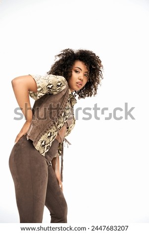 tasteful african american fashionista in trendy outfit with animalistic print looking at camera