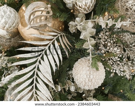 Tasteful silver, white and gold Christmas tree decorations having on green fir tree