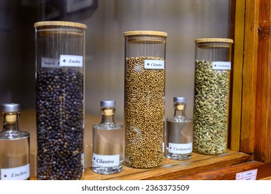 Tastes of gin, botanicals ingredient for gin distillery process, name in Spaniish translated into English: juniper, coriander and cardamom, dried coriander seeds in glass pot - Powered by Shutterstock