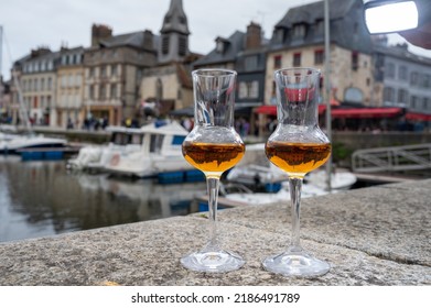Tasting of apple calvados drink from glasses in old Honfleur harbour with boats and old houses on background, Normandy, France - Shutterstock ID 2186491789