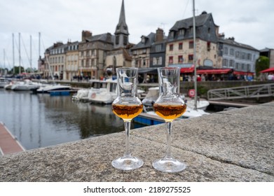 Tasting Of Apple Calvados Drink From Glasses In Old Honfleur Harbour With Boats And Old Houses On Background, Normandy, France