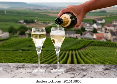 Tasting of brut and demi-sec white champagne sparkling wine from special flute glasses with view on green Champagne vineyards, France