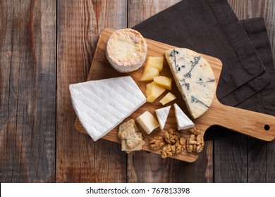 Tasting cheese dish on a wooden plate. Food for wine and romantic, cheese delicatessen on a wooden rustic table. Top view with copy space. - Powered by Shutterstock