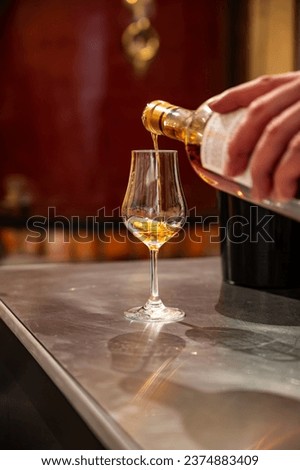 Tasting of cognac spirit aged in old dark French oak barrels in cellar in distillery house, Cognac white wine region, Charente, Segonzac, Grand Champagne, France