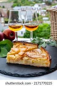Tasting of fresh baked apple cake and strong alcoholic drink calvados made from apples in Normandy and view on old houses in Norman village, Calvados region, France