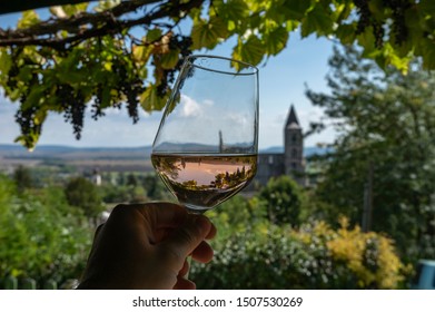 Tasting A Glass Of Rose Wine In Zsambek, Hungary Which Is Part Of The Etyek Wine Region. In The Background There Is The Old Monastery Church Ruin.