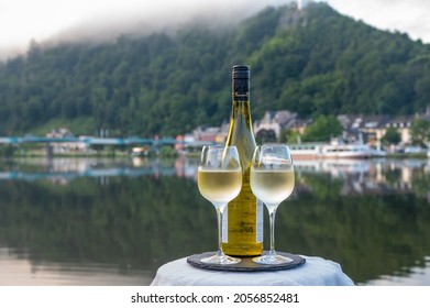 Tasting of white quality riesling wine served on outdoor terrace in Mosel wine region with Mosel river and old German town on background in sunny day, Germany