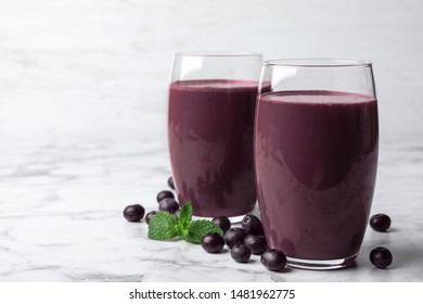 Tasty Acai Drink In Glasses And Berries On Marble Table