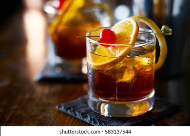 tasty alcoholic old fashioned cocktail with orange slice, cherry, and lemon peel garnish
