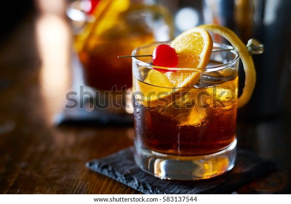 tasty alcoholic old fashioned cocktail\
with orange slice, cherry, and lemon peel\
garnish