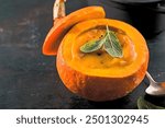 Tasty appetizing beautiful pumpkin soup in the whole pumpkin with bread and spices ready to eat on table Closeup