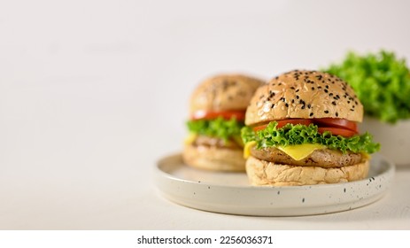 Tasty beef burgers with fresh vegetables and cheese on minimal ceramic plate, white background. American fast food concept - Shutterstock ID 2256036371