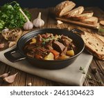 Tasty beef stew with vegetables, placed in the center of a rustic table surrounded by spices, fresh herbs, and toasted bread slices.