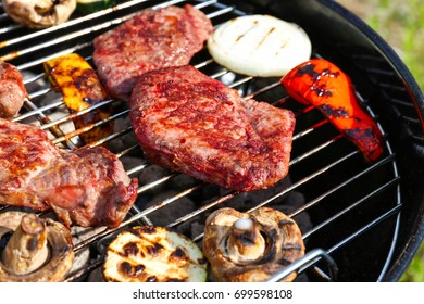 Tasty beefsteaks and vegetables cooking on barbecue grill - Shutterstock ID 699598108