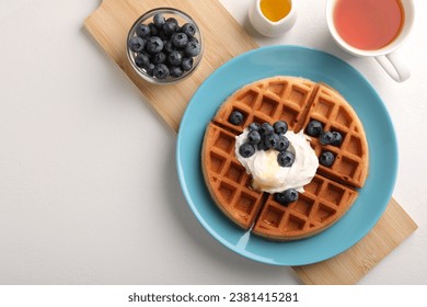 Tasty Belgian waffle with blueberries, honey and whipped cream served on white table, flat lay. Space for text - Powered by Shutterstock