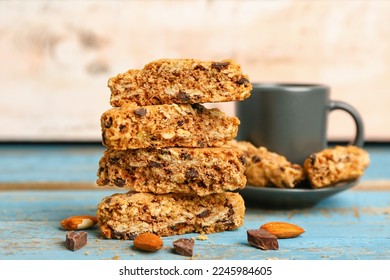 Tasty biscotti cookies, almond nuts, chocolate and cup on blue wooden table