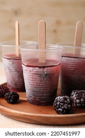 Tasty Blackberry Ice Pops In Plastic Cups On White Table, Closeup. Fruit Popsicle