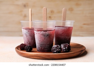 Tasty Blackberry Ice Pops In Plastic Cups On White Table. Fruit Popsicle