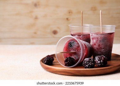 Tasty Blackberry Ice Pops In Plastic Cups On White Table, Space For Text. Fruit Popsicle