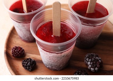 Tasty Blackberry Ice Pops In Plastic Cups On Table, Closeup. Fruit Popsicle