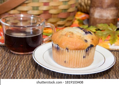 Tasty blueberry muffin with piping hot cup of coffee in an autum setting.  This is the epitome of a fresh breakfast snack setting for restaurants and home bakery promotion.