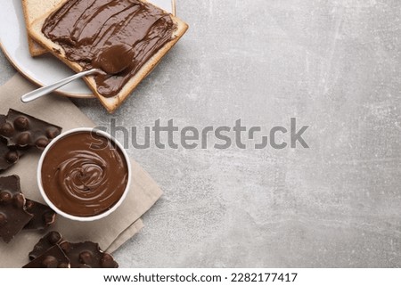 Tasty breakfast. Flat lay composition with sweet paste and chocolate pieces served on grey textured table. Space for text