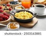 Tasty breakfast. Scrambled eggs, coffee, jam and other food on grey textured table, closeup