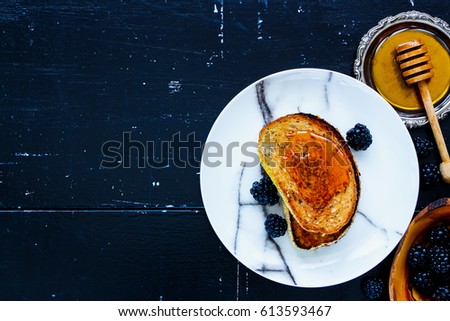 Tasty breakfast theme. Grilled whole grain toasts with honey and fresh blackberries on vintage wooden background. Top view. With copy space. Flat lay style