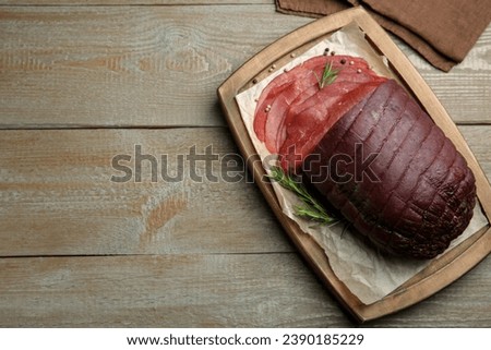 Tasty bresaola, peppercorns and rosemary on wooden table, top view. Space for text