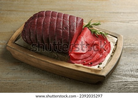 Tasty bresaola, peppercorns and rosemary on wooden table
