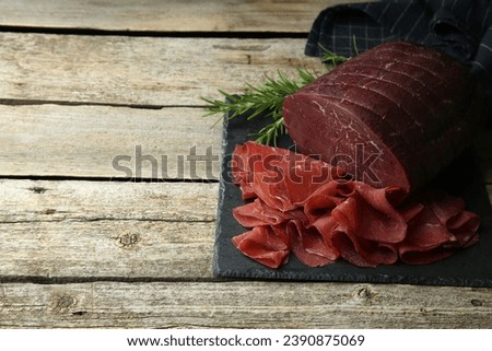 Tasty bresaola and rosemary on wooden table. Space for text