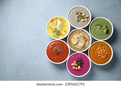 Tasty broth and different cream soups in bowls on gray table, flat lay. Space for text - Shutterstock ID 2395421791