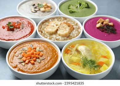 Tasty broth and different cream soups in bowls on gray table, closeup - Shutterstock ID 2395421835