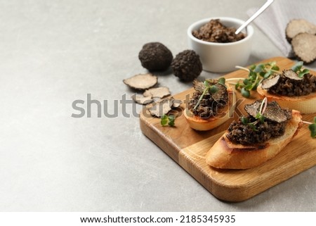Tasty bruschettas with truffle paste on grey table, space for text