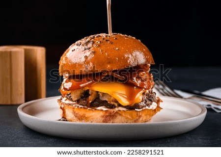 Tasty burger cooking with beef, tomato, cheese, cucumber and lettuce. American food burger with beef, sausage, cheddar cheese, ketchup and mayonnaise.
