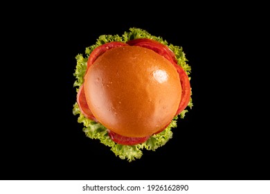 Tasty Burger With Lettuce Leaf, Slices Tomatoes And Cutlet In Appetizing Bun. Burger Isolated On Black Background Shot From Above. 