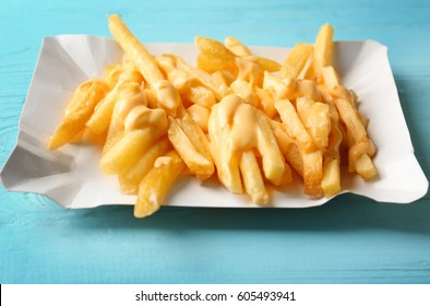 Tasty cheese fries on blue wooden table
