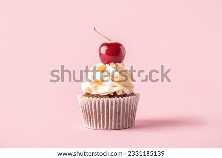 Tasty cherry cupcake on pink background