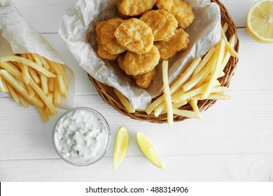 Tasty chicken nuggets with lemon, fries and sauce on table