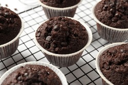 Tasty Chocolate Muffins And Cooling Rack On White Table, Closeup