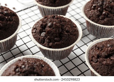 Tasty chocolate muffins and cooling rack on white table, closeup - Powered by Shutterstock