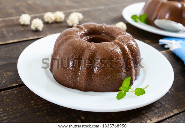 Tasty chocolate\
pudding on white plates on a dark wooden background. Light\
low-calorie dessert for\
breakfast.