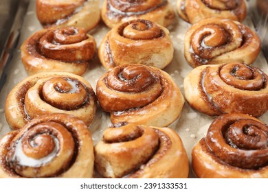Tasty cinnamon rolls with cream on parchment paper, closeup - Shutterstock ID 2391333531