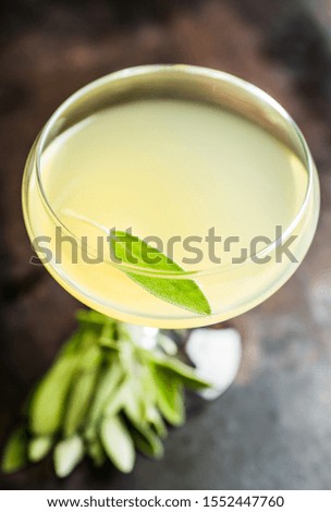 Tasty cocktail with limoncello and sage leaves on the rustic background. Shallow depth of field. Selective focus.