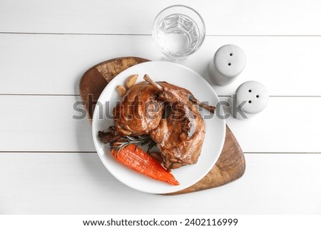 Tasty cooked rabbit meat served on white wooden table, flat lay
