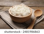 Tasty cooked rice in bowl and spoon on wooden table