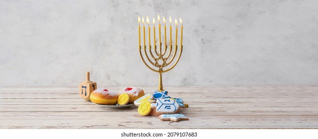 Tasty cookies and donuts for Hanukkah celebration with menorah on light background with space for text
