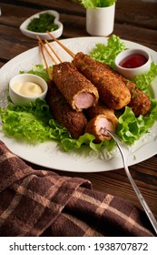 Tasty Corn Dog With Sauce And Salad Served On White Plate On Wooden Table